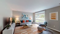 This single-floor residence offers a thoughtfully designed layout that balances comfort and functionality across its key living spaces. The living room serves as the heart of the home, featuring dark hardwood-style flooring, neutral gray walls, and a large picture window that frames lush green outdoor views while flooding the space with natural light. The open sightline connects the living area directly to the dining space and kitchen, creating a seamless flow ideal for everyday living and entertaining. The galley-style kitchen is efficiently organized with two-tone cabinetry — white uppers and gray lowers — paired with light countertops and black appliances including a gas range, refrigerator, and dishwasher. A convenient in-unit stacked washer and dryer is tucked just off the kitchen. The bedroom is a comfortable retreat with plush carpeting, dual reach-in closets providing generous storage, and a window that invites natural light. Unique pendant light fixtures add a decorative touch to the bedroom's ambiance. The bathroom features a clean, modern aesthetic with gray cabinetry, a white countertop vanity, a full tub-shower combination, and wood-style flooring. Throughout the residence, consistent design choices create a cohesive and inviting atmosphere.