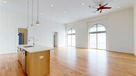 Located at 3215 Stuart Ave in Richmond, VA's 23221 zip code, this thoughtfully designed 2-bedroom, 2-bathroom single-floor residence offers a generous and well-appointed living experience. The open-concept kitchen and living area serves as the heart of the home, anchored by a large center island with a white quartz countertop, warm natural wood cabinetry, open shelving, stainless steel appliances including a double wall oven and refrigerator, and sleek pendant lighting. Soaring ceilings and dramatic arched windows flood the living space with abundant natural light, while light hardwood flooring extends throughout, creating a warm and cohesive aesthetic. The living area features arched floor-to-ceiling windows and access to a balcony through arched French doors, offering outdoor views of the surrounding neighborhood. The bedrooms are well-sized, with the primary bedroom also showcasing a signature arched window. Both bathrooms are finished in a clean, contemporary style, featuring hex tile flooring, full tub-shower combinations with subway tile surrounds, and illuminated vanity mirrors. A dedicated laundry room with full-size washer and dryer units and overhead cabinetry adds everyday convenience. Multiple closets provide ample storage throughout the home.