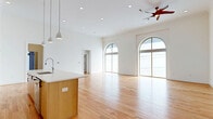 Located at 3215 Stuart Ave in Richmond, VA's 23221 zip code, this thoughtfully designed 2-bedroom, 2-bathroom single-floor residence offers a generous and well-appointed living experience. The open-concept kitchen and living area serves as the heart of the home, anchored by a large center island with a white quartz countertop, warm natural wood cabinetry, open shelving, stainless steel appliances including a double wall oven and refrigerator, and sleek pendant lighting. Soaring ceilings and dramatic arched windows flood the living space with abundant natural light, while light hardwood flooring extends throughout, creating a warm and cohesive aesthetic. The living area features arched floor-to-ceiling windows and access to a balcony through arched French doors, offering outdoor views of the surrounding neighborhood. The bedrooms are well-sized, with the primary bedroom also showcasing a signature arched window. Both bathrooms are finished in a clean, contemporary style, featuring hex tile flooring, full tub-shower combinations with subway tile surrounds, and illuminated vanity mirrors. A dedicated laundry room with full-size washer and dryer units and overhead cabinetry adds everyday convenience. Multiple closets provide ample storage throughout the home.