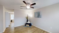This single-story, three-bedroom, two-bathroom home delivers a well-organized layout designed for comfortable everyday living. The interior features warm-toned wood-look flooring that runs throughout, lending a cohesive and inviting feel to the space. White walls provide a clean, neutral backdrop that enhances the sense of openness and allows for versatile decorating possibilities.

The living area is highlighted by a ceiling fan with a built-in light fixture, offering both comfort and ambient illumination. A textured ceiling adds subtle architectural character, while natural light filters in through a window, brightening the room throughout the day. Crisp white baseboards frame the flooring neatly, contributing to the home's tidy, well-maintained appearance.

The thoughtful single-floor plan makes the home easily navigable, with three bedrooms providing ample space for rest, work, or guests. Two full bathrooms add convenience for residents and visitors alike. Overall, the home strikes a balance between practical functionality and comfortable style, making it a welcoming space suited for a variety of lifestyles.