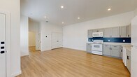 This thoughtfully designed 2-bedroom, 2-bathroom home offers a clean, modern aesthetic across a single floor. Light hardwood flooring runs throughout the entire space, creating a cohesive and airy feel. The open-concept kitchen and living area serves as the heart of the home, featuring gray shaker-style cabinets with matte black hardware, a bold navy blue subway tile backsplash, light countertops, and white appliances including a range, over-the-range microwave, and dishwasher. Recessed lighting illuminates the expansive living area, which offers ample room for a variety of furniture arrangements. Both bedrooms are generously sized, with tall ceilings, natural light from windows with blinds, and double-door closets. The primary bedroom includes a ceiling fan and multiple windows. Each bathroom is finished with elegant gold hardware and a tub-shower combo with white tile surround. One bathroom features a standout blue vanity with a marble-style countertop and a decorative gold-framed mirror, adding a stylish focal point. Two additional closets provide practical storage throughout the home. The overall ambiance is bright, clean, and move-in ready.
