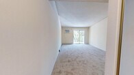 Located at 1860 52nd St E in Inver Grove Heights, MN, this two-bedroom, one-bathroom unit offers a practical and comfortable single-floor layout. The living room is generously sized, featuring wall-to-wall carpet, a sliding glass door that opens to a balcony with tree-lined views, and a wall-mounted air conditioning unit alongside baseboard heating. The open connection to the kitchen creates an easy flow between living and dining areas. The galley-style kitchen is well-appointed with ample upper and lower cabinetry in a light wood and white finish, a white appliance suite including a refrigerator, electric range, and over-the-range microwave, and durable tile flooring beneath a bright skylight and ceiling fan. Both bedrooms are carpeted and include baseboard heating; the primary bedroom features a mirrored sliding closet and access to a walk-in closet with built-in shelving rods. A second carpeted bedroom offers a ceiling fan and a large window with leafy outdoor views. The full bathroom includes tile flooring, a vanity with storage, and a tub/shower combination. A hallway connects all rooms, completing this well-organized and functional floor plan.