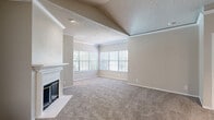 Located at 600 S MacArthur Blvd in Coppell, TX, this single-floor, three-bedroom, two-bathroom residence offers a well-organized layout with a welcoming entrance, hallway, utility room, and two closets. The spacious living room is a standout feature, boasting vaulted ceilings with crown molding, a textured ceiling, a classic white-mantled fireplace, and large multi-pane windows that flood the room with natural light. Soft, neutral-toned carpet runs throughout the living and bedroom areas, contributing to a warm and cohesive ambiance. The kitchen is open and functional, featuring light wood cabinetry, bold dark speckled countertops, a breakfast bar peninsula, wood-look flooring, and white appliances. The generously sized primary bedroom offers ample space and natural light through multiple windows. The additional bedrooms are well-proportioned, each equipped with ceiling fans and windows with blinds. The bathrooms include a tub-shower combo with tile surround and light wood vanity cabinetry with white countertops. Throughout, the home maintains a neutral color palette with beige walls and white trim, creating a clean, move-in-ready atmosphere suited for comfortable everyday living.