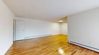 This well-appointed one-bedroom, one-bathroom residence in Perth Amboy, NJ offers a thoughtfully designed single-floor layout with an efficient use of space throughout. Gleaming hardwood floors flow seamlessly across the living room, bedroom, and connecting areas, lending warmth and continuity to the interior.

The open living room is bright and welcoming, featuring natural light from large windows with blinds and a wall-mounted air conditioning unit alongside baseboard heating for year-round comfort. The space connects to a galley-style kitchen, which is outfitted with rich dark wood cabinetry, granite countertops, a marble-style tile backsplash, stainless steel appliances including a gas range and refrigerator, and a undermount sink — a well-equipped space for home cooking.

The bedroom is generously proportioned, offering dual closets with sliding and hinged doors for ample storage, along with windows that bring in natural light and views of the surrounding greenery. Light-toned hardwood floors continue throughout.

The bathroom is elegantly finished with marble-style wall tile surrounding a full soaking tub with a glass panel, complemented by a dark wood vanity with a granite countertop and chrome fixtures, creating a clean, refined aesthetic. This residence combines functional design with quality finishes throughout.