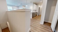 This thoughtfully designed single-floor residence offers a functional and modern layout across a comfortable footprint. The open-concept living and kitchen area serves as the heart of the home, highlighted by a large granite-topped island with an undermount sink and elegant pendant lighting overhead. The kitchen is outfitted with crisp white upper cabinetry, gray lower cabinets with brushed gold hardware, granite countertops, and a full suite of stainless steel appliances including a range, microwave, dishwasher, and refrigerator. Light wood-look flooring flows throughout the main living areas, enhancing the bright, airy atmosphere created by recessed lighting and natural light from multiple windows. The spacious bedroom features plush carpeting, a ceiling fan, and a large window that fills the room with natural light. A dedicated closet provides ample storage. The full bathroom is cleanly finished with white subway tile surrounding a soaking tub and shower combination, complemented by brushed nickel fixtures. A separate laundry room houses a full-size washer with overhead wire shelving. A hallway connects all rooms, completing this efficiently designed and move-in-ready residence.
