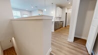 This thoughtfully designed single-floor residence offers a functional and modern layout across a comfortable footprint. The open-concept living and kitchen area serves as the heart of the home, highlighted by a large granite-topped island with an undermount sink and elegant pendant lighting overhead. The kitchen is outfitted with crisp white upper cabinetry, gray lower cabinets with brushed gold hardware, granite countertops, and a full suite of stainless steel appliances including a range, microwave, dishwasher, and refrigerator. Light wood-look flooring flows throughout the main living areas, enhancing the bright, airy atmosphere created by recessed lighting and natural light from multiple windows. The spacious bedroom features plush carpeting, a ceiling fan, and a large window that fills the room with natural light. A dedicated closet provides ample storage. The full bathroom is cleanly finished with white subway tile surrounding a soaking tub and shower combination, complemented by brushed nickel fixtures. A separate laundry room houses a full-size washer with overhead wire shelving. A hallway connects all rooms, completing this efficiently designed and move-in-ready residence.