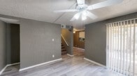 Located at 2900 S Fifth St in Garland, TX, this two-story, 3-bedroom, 2-bathroom home offers a practical and comfortable layout across two floors. The main level hosts the living room, dining room, and kitchen, while the upper level accommodates the bedrooms and bathrooms.

The living room features light wood-look flooring, a textured gray accent wall, and a ceiling fan with light fixture. A staircase connects the two levels, and sight lines from the living area extend into the kitchen beyond.

The kitchen is galley-style with crisp white cabinetry, granite-look countertops, a double stainless steel sink, black appliances including an electric range and refrigerator, and a mosaic tile backsplash. A back door provides secondary access from the kitchen.

Upstairs, the three bedrooms each feature the same light wood-look flooring, ceiling fans, textured walls, and closet space. The primary bedroom includes two closets and a large window with vertical blinds that allows natural light. The two bathrooms are appointed with white vanities, granite-look countertops, and tiled tub-shower combinations. Textured walls carry throughout the home, giving each room a consistent, cohesive character.