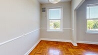 Located on the fourth floor at 6817 Georgia Ave NW in Washington, DC, Unit 405 is a well-appointed one-bedroom, one-bathroom residence that makes efficient use of its space. Throughout the living and bedroom areas, warm-toned parquet hardwood flooring in a classic basket-weave pattern adds character and a timeless aesthetic to every room.

The open living and dining area is brightened by natural light streaming through large windows that offer tree-lined views of the surrounding neighborhood. A ceiling fan overhead provides added comfort, while neutral gray walls create a clean, versatile backdrop. An elegant arched doorway connects the living area to the rest of the unit, adding an architectural charm.

The generously sized bedroom features the same distinctive parquet flooring, large windows with outdoor views, a ceiling fan, and a sizable closet, providing ample storage.

The galley-style kitchen is outfitted with warm wood cabinetry, dark granite-style countertops, a gas range, stainless steel sink, and a full-size refrigerator — offering a practical and well-equipped cooking space.

The bathroom is clean and functional, featuring a white vanity with a single-basin sink, a mirror, and a full shower-tub combination with white tile surround and a curtain rod. Light tile flooring completes the crisp, bright finish of the space.