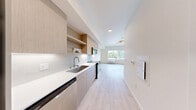 Located at 4028 196th St SW in Lynnwood, Washington, this thoughtfully designed single-floor studio unit offers a clean, contemporary aesthetic throughout. The open-concept kitchen and living area is anchored by light wood-style flooring that extends seamlessly across the space, creating a bright and cohesive feel. A large picture window floods the living area with natural light while framing views of the surrounding tree-lined neighborhood and Lynnwood streetscape. A modern ring chandelier adds a stylish focal point overhead, while a wall-mounted PTAC unit provides in-unit climate control.

The kitchen is outfitted with flat-front cabinetry in a warm wood finish, white quartz countertops, a subway tile backsplash, and stainless steel appliances including a range, over-the-range microwave, and refrigerator. Open shelving above the cabinetry adds both storage and visual interest.

A sliding door leads to a dedicated closet area, offering organized storage within the efficient floor plan. The bathroom features light wood-style flooring consistent with the rest of the unit, a soaking tub, toilet, and a vanity with warm wood cabinetry. Clean white walls and brushed nickel fixtures contribute to the space's modern, understated character throughout.