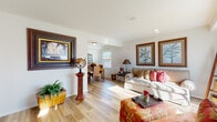 This two-floor home exudes a relaxed, tropical warmth through its thoughtfully curated interiors and cohesive design. The main living area is anchored by light hardwood flooring that flows seamlessly throughout, complementing crisp white walls adorned with bamboo-framed botanical artwork. The spacious living room accommodates generous seating and opens directly into the dining area, where natural light pours in through a large window, illuminating a rattan dining set and a decorative wall mirror. Tropical accents, including globe displays and lush greenery, add character throughout the common areas.

The kitchen is well-appointed with rich, dark espresso cabinetry, light quartz countertops, a tile backsplash, and full-size appliances, offering ample storage and functionality. Adjacent to the kitchen, the dining nook provides an intimate setting for meals.

The bedrooms are comfortably sized, each with windows that invite natural light and soft neutral walls. One bedroom features warm wood furnishings, while another offers a cozy, compact layout ideal as a guest room. The bathroom is clean and classic, featuring a tub-shower combination with tile surround, dark wood vanity, and light hardwood-style flooring, completing the home's warm and cohesive aesthetic.