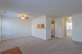 Located at 100 Bridgeport Cove Dr in Hampton, Virginia, this single-floor residence offers a clean, functional layout designed for comfortable everyday living. The open living area greets you at the entrance, featuring plush carpet flooring, a ceiling fan, and multiple windows fitted with blinds that allow ample natural light to fill the space. A pass-through window connects the living area to the galley-style kitchen, which is equipped with warm wood cabinetry, dark laminate countertops, a coil-burner electric range, a full-size refrigerator, and hardwood-style flooring throughout. Two full bathrooms serve the home — each featuring a wood vanity with a white countertop, a tub-shower combination, and a large mirror. One bathroom includes hardwood-style flooring, while the other is finished with matching wood-look floors and contemporary light fixtures. The bedrooms are carpeted and well-lit by natural light from large windows. One bedroom features a dedicated walk-in closet with wire shelving, offering generous storage capacity. An additional standard closet with rod storage is found in another bedroom. The home's neutral color palette and consistent finishes throughout create a cohesive and move-in-ready environment.