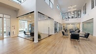 Located at 1 Forest Ridge Blvd in Saratoga Springs, NY, this impressive two-story amenity building offers a wide array of recreational and functional spaces across a generously sized footprint. The main floor commands the majority of the space and serves as the hub for activity, while the upper level provides additional room for gathering and recreation.

The modern interior greets visitors with a bright, glass-enclosed lobby featuring light hardwood flooring, sleek leather seating, and large windows that flood the entry with natural light. A stylish lounge area with floor-to-ceiling frosted glass partitions and contemporary furnishings invites relaxation and social interaction.

Recreational amenities are a clear highlight. An indoor lap pool with soaring double-height ceilings and expansive glass doors opens to an outdoor patio, creating a seamless indoor-outdoor experience. A dedicated indoor basketball court with hardwood floors and high ceilings provides ample space for active play. The upper level hosts a game room complete with pool tables, a cable-rail mezzanine, and dramatic floor-to-ceiling windows.

A private conference room with large black-framed windows and views of the surrounding landscape offers a professional setting for meetings. Outdoors, the landscaped grounds feature tiered stone retaining walls, manicured lawns, stone-paved pathways, and a wooded backdrop, creating a serene natural setting.