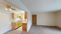 This single-floor residential unit offers a functional and straightforward layout designed for comfortable everyday living. The open-concept design connects the kitchen directly to the living area, creating a cohesive and practical flow throughout the main living space. The kitchen is well-appointed with light wood cabinetry, ample upper and lower storage, laminate countertops, a double-basin stainless steel sink, a white electric range, a refrigerator, and a microwave. Light tile flooring runs throughout the kitchen, adding easy-to-clean practicality. The spacious living room features wall-to-wall carpeting and is bathed in natural light through a large sliding glass door fitted with vertical blinds, which opens to an outdoor balcony. A wall-mounted air conditioning unit and baseboard heating ensure year-round comfort. The bedroom is generously sized with plush carpeting, a wide window that brings in natural light, and baseboard heating. The full bathroom includes a single-sink vanity with wood cabinetry, a mirrored medicine cabinet with overhead lighting, a toilet, and a full-size soaking tub with a shower and sliding glass enclosure. Tile flooring completes the bathroom. Throughout the unit, neutral wall tones and clean lines create a calm, move-in-ready atmosphere.