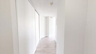 Located at 200–230 Denistoun Street in Welland, Ontario, this one-bedroom, one-bathroom unit offers a thoughtfully laid-out single-floor plan with a clean, bright aesthetic throughout. Light wood-style luxury vinyl flooring flows continuously across the entire space, complemented by crisp white walls and textured ceilings that give each room a fresh, well-maintained feel.

The open-concept living, dining, and kitchen area forms the heart of the unit, providing a generous, versatile space ideal for everyday living. Large windows dressed with vertical blinds invite ample natural light into the living area, and a baseboard heating unit runs along the exterior wall. The kitchen is efficiently positioned and connects seamlessly to the main living space.

The bedroom is a comfortable, well-sized room featuring a built-in sliding-door closet, a window with an outdoor view of surrounding greenery, and the same warm flooring found throughout. A hallway with an additional sliding-door storage closet connects the bedroom to the rest of the unit, adding practical storage solutions.

The bathroom is clean and functional, featuring a full tub-and-shower surround with chrome fixtures. Overall, the unit presents a light, neutral palette and a practical layout suited for comfortable, everyday living.