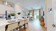 Located at 5020 Cedar Leaf Circle in Palmetto, FL, this well-appointed single-floor home offers a thoughtfully designed open-concept layout that maximizes every square foot. Light wood-look flooring flows throughout, creating a warm and cohesive aesthetic.

The kitchen is a standout feature, showcasing crisp white shaker cabinetry extending to the ceiling, gleaming quartz countertops, a full suite of stainless steel appliances including a French door refrigerator, range, built-in microwave, and dishwasher, plus a peninsula with seating — ideal for casual dining. A pendant light adds an elegant finishing touch.

The living room is bright and inviting, featuring a ceiling fan, recessed lighting, and sliding glass doors that open to the outdoors, filling the space with natural light and greenery views. The open sightline to the kitchen enhances the sense of spaciousness.

The bedroom is a serene retreat, comfortably sized with large windows that invite natural light. It connects directly to a well-designed full bathroom featuring a dual-sink vanity with white cabinetry, quartz countertops, and a large mirror. A dedicated walk-in closet with built-in shelving and hanging rods completes the private quarters, offering practical and organized storage.