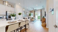 Located at 5020 Cedar Leaf Circle in Palmetto, FL, this well-appointed single-floor home offers a thoughtfully designed open-concept layout that maximizes every square foot. Light wood-look flooring flows throughout, creating a warm and cohesive aesthetic.

The kitchen is a standout feature, showcasing crisp white shaker cabinetry extending to the ceiling, gleaming quartz countertops, a full suite of stainless steel appliances including a French door refrigerator, range, built-in microwave, and dishwasher, plus a peninsula with seating — ideal for casual dining. A pendant light adds an elegant finishing touch.

The living room is bright and inviting, featuring a ceiling fan, recessed lighting, and sliding glass doors that open to the outdoors, filling the space with natural light and greenery views. The open sightline to the kitchen enhances the sense of spaciousness.

The bedroom is a serene retreat, comfortably sized with large windows that invite natural light. It connects directly to a well-designed full bathroom featuring a dual-sink vanity with white cabinetry, quartz countertops, and a large mirror. A dedicated walk-in closet with built-in shelving and hanging rods completes the private quarters, offering practical and organized storage.