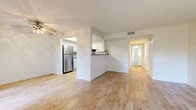 Located at 2345 Newport Blvd in Costa Mesa, California, this single-floor, 3-bedroom, 2-bathroom home offers a clean and functional layout with a bright, neutral aesthetic throughout. The open living area is anchored by light wood-style flooring and a ceiling fan, with natural light filtering in through vertical-blind windows. A half-wall partition connects the living room to the kitchen, which features white shaker cabinetry, subway tile backsplash, stainless steel appliances including a refrigerator, gas range with over-the-range microwave, and dishwasher, all set on matching light wood flooring. A dedicated hallway leads to the three bedrooms, which are finished with plush carpet and windows providing natural light. One bedroom includes a sliding closet. The two bathrooms mirror each other in style, each featuring a white vanity with grey stone countertops, framed mirrors, and wood-style flooring. A dedicated closet provides additional storage. The unit also includes a private outdoor patio with stucco surround, ideal for outdoor relaxation. Clean white walls and consistent finishes throughout give the home a cohesive, move-in-ready feel.