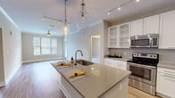 Located at 2875 Crescent Pkwy in Atlanta, Georgia, this well-appointed 2-bedroom, 2-bathroom residence offers a thoughtfully designed single-level layout. The open-concept kitchen and living area serves as the heart of the home, showcasing a large center island with quartz countertops, a deep undermount sink, and elegant teardrop pendant lighting. Crisp white cabinetry with glass-front uppers, a subway tile backsplash, and a full suite of stainless steel appliances — including a French door refrigerator, electric range with over-the-range microwave — complete the kitchen. Hardwood-style flooring flows throughout the main living areas, while the living room benefits from natural light through large windows and is outfitted with crown molding and a ceiling fan. Both bedrooms offer plush carpeting and dedicated closet space, with the primary bedroom providing a comfortable, well-scaled retreat. Each bathroom features tile flooring, a tub-shower combination with tiled surround, and quartz-topped vanities with chrome fixtures. Two hallways connect the layout efficiently, and two closets provide ample storage throughout the residence.