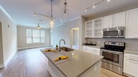 Located at 2875 Crescent Pkwy in Atlanta, Georgia, this well-appointed 2-bedroom, 2-bathroom residence offers a thoughtfully designed single-level layout. The open-concept kitchen and living area serves as the heart of the home, showcasing a large center island with quartz countertops, a deep undermount sink, and elegant teardrop pendant lighting. Crisp white cabinetry with glass-front uppers, a subway tile backsplash, and a full suite of stainless steel appliances — including a French door refrigerator, electric range with over-the-range microwave — complete the kitchen. Hardwood-style flooring flows throughout the main living areas, while the living room benefits from natural light through large windows and is outfitted with crown molding and a ceiling fan. Both bedrooms offer plush carpeting and dedicated closet space, with the primary bedroom providing a comfortable, well-scaled retreat. Each bathroom features tile flooring, a tub-shower combination with tiled surround, and quartz-topped vanities with chrome fixtures. Two hallways connect the layout efficiently, and two closets provide ample storage throughout the residence.