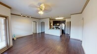 This single-story residence in Tomball, TX offers a thoughtfully designed open-concept layout that seamlessly connects the living area and kitchen. Rich, dark hardwood-style flooring flows throughout the main living spaces, complemented by crown molding and ceiling fans that add a polished finish. The expansive living area is bathed in light and features track lighting along one wall, with elegant arched doorways providing a classic architectural touch.

The kitchen is a functional centerpiece, boasting dark espresso cabinetry, granite countertops, stainless steel appliances including a refrigerator, microwave, and range, and a peninsula with a double sink — ideal for both cooking and casual dining. Pendant lighting above the peninsula enhances the space's warm ambiance.

The bedrooms feature plush wall-to-wall carpeting, ceiling fans, and windows dressed with blinds that allow for natural light and outside views. The layout from the floorplan model reveals multiple bedrooms, offering ample living flexibility.

The bathroom is finished with classic checkered tile accents in the tub-shower surround and connects conveniently to a walk-in closet with built-in shelving. Throughout the home, neutral tones and clean lines create a versatile, move-in-ready environment suitable for a variety of lifestyles.