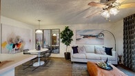 This single-story residence offers a thoughtfully designed layout that balances comfort and style across its key living areas. The open-concept living and dining space serves as the heart of the home, where wood-look flooring, a ceiling fan, and a large sliding glass door leading to a private patio create a bright and inviting atmosphere. A bold landscape artwork anchors the living area, which flows seamlessly into the dining space. The dining area makes a striking impression with a round white table, sleek wire chairs, a statement pendant light, and a large-scale abstract mural that adds artistic energy to the room. Full-length framed mirrors reflect the space, enhancing the sense of openness. The galley kitchen is functional and well-equipped, featuring warm wood cabinetry, white countertops, and light-toned flooring, with a skylight adding a touch of brightness overhead. Both bedrooms are carpeted and comfortably proportioned, each offering windows with vertical blinds for privacy and light control. The primary bathroom features a wood-toned vanity with ample cabinetry, a large mirror, and warm lighting, while the full bath includes a tub-shower combination. Throughout, textured ceilings and neutral walls provide a clean, versatile backdrop for the home's contemporary furnishings.