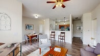 Located at 1021 Stoneridge Dr in Seymour, Indiana, this single-floor, 2-bedroom, 2-bathroom home offers a thoughtfully designed open-concept layout. The combined living and dining area forms the heart of the home, featuring durable wood-style flooring, neutral walls, and a ceiling fan with light fixture overhead. A large window in the living room fills the space with natural light and provides views of the surrounding neighborhood. The kitchen is positioned adjacent to the living and dining areas, separated by a raised bar-height counter with pendant lighting above. Rich warm-toned cabinetry, dark granite countertops, and black appliances — including a range, microwave, and refrigerator — define the kitchen's functional character. The dining area comfortably accommodates a four-person table and connects smoothly to the rest of the main living space. Both bedrooms offer carpet flooring and generous closet space, including a walk-in closet with wire shelving for ample storage. The bathrooms feature warm wood cabinetry, granite-topped vanities, and combination tub/shower configurations with wood-style flooring. A dedicated laundry area with side-by-side washer and dryer adds everyday convenience. Hallways connect each area cleanly, maintaining an organized and efficient flow throughout the home.