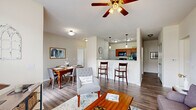 Located at 1021 Stoneridge Dr in Seymour, Indiana, this single-floor, 2-bedroom, 2-bathroom home offers a thoughtfully designed open-concept layout. The combined living and dining area forms the heart of the home, featuring durable wood-style flooring, neutral walls, and a ceiling fan with light fixture overhead. A large window in the living room fills the space with natural light and provides views of the surrounding neighborhood. The kitchen is positioned adjacent to the living and dining areas, separated by a raised bar-height counter with pendant lighting above. Rich warm-toned cabinetry, dark granite countertops, and black appliances — including a range, microwave, and refrigerator — define the kitchen's functional character. The dining area comfortably accommodates a four-person table and connects smoothly to the rest of the main living space. Both bedrooms offer carpet flooring and generous closet space, including a walk-in closet with wire shelving for ample storage. The bathrooms feature warm wood cabinetry, granite-topped vanities, and combination tub/shower configurations with wood-style flooring. A dedicated laundry area with side-by-side washer and dryer adds everyday convenience. Hallways connect each area cleanly, maintaining an organized and efficient flow throughout the home.