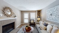 This single-floor residence offers a thoughtfully designed layout with a warm, neutral color palette of taupe and greige tones carried throughout. The living room serves as a central gathering space, anchored by a stone-surround fireplace with a white mantle and flanked by built-in corner shelving. Two windows fitted with blinds allow natural light to fill the room, while wood-look flooring adds warmth underfoot.

Adjacent to the living area, a dedicated dining space features wood-look flooring and a pendant light fixture overhead, creating an intimate setting for everyday meals. The galley-style kitchen is outfitted with white shaker cabinetry, white quartz countertops, a subway tile backsplash, a stainless steel sink, and black appliances including a refrigerator, range, microwave, and dishwasher. A window above the sink adds natural light, and a closet provides additional storage.

The bedroom is carpeted and comfortably sized, featuring a ceiling fan, a natural light source from a window, and access to a walk-in closet. The full bathroom includes a white vanity with shaker-style cabinetry, a framed mirror, wood-look flooring, and a tub-shower combination, maintaining the clean, cohesive aesthetic found throughout the residence.