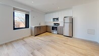 Unit 302 is a thoughtfully designed 1-bedroom, 1-bathroom residence that showcases a clean, modern aesthetic throughout its single-floor layout. The open-concept kitchen is a standout feature, outfitted with a full suite of stainless steel appliances — including a refrigerator, electric range, and over-the-range microwave — complemented by a two-tone cabinet design that pairs warm wood-finish lower cabinets with crisp white upper cabinets. Light hardwood-style flooring flows seamlessly throughout the entire unit, creating a cohesive and airy feel. Recessed lighting and a window allowing natural light enhance the brightness of the living and kitchen areas. The bedroom is generously proportioned, offering a double-door closet for ample storage, a wall-mounted mini-split HVAC unit for individualized climate control, and convenient access to an in-unit stacked washer and dryer. A barn-style sliding door adds a stylish architectural detail. The bathroom is finished with elegant floor-to-ceiling marble-patterned tile in the walk-in glass-enclosed shower, with coordinating tile flooring and modern fixtures. The overall ambiance is bright, clean, and contemporary, making this a well-appointed and functional residence.
