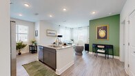 Located at 5420 Giles St in Norcross, GA, this thoughtfully designed two-bedroom, two-bathroom residence offers a comfortable and modern living experience on a single level. The open-concept layout connects the kitchen and living room seamlessly, creating a bright and inviting communal space. The kitchen is equipped with sleek gray cabinetry, granite countertops, stainless steel appliances including a French door refrigerator, electric range, microwave, and dishwasher, along with a central island that provides additional workspace and seating. Light wood-style flooring flows throughout, complementing the clean white walls and contemporary finishes. The living area is bathed in natural light from multiple windows dressed with sheer curtains and wood blinds, with an accent wall in sage green adding a touch of warmth and character. Both bedrooms feature neutral accent walls, ceiling fans, and ample natural light, with the primary bedroom offering direct access to its own bathroom. The two bathrooms are finished with granite vanities, gray cabinetry, and wood-style flooring, with one featuring a full tub-shower combination. A dedicated closet provides convenient storage. The overall ambiance is modern, clean, and welcoming throughout.