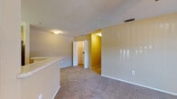 This single-floor residential unit offers a functional and well-organized layout across several rooms. The living area is spacious and finished with wall-to-wall carpeting in a neutral tone, anchored by a ceiling fan with integrated lighting. Large windows with vertical blinds invite natural light and provide views of the surrounding greenery. A half-wall with a light-toned countertop separates the living space from the kitchen, creating an open, connected feel.

The kitchen is equipped with light wood cabinetry, a double-basin sink, a white electric range, and a refrigerator, all set atop easy-care tile flooring. The warm, golden-toned walls carry throughout the unit, lending a cohesive and inviting atmosphere.

The unit includes multiple bedrooms, each carpeted and featuring windows that bring in natural light. The rooms are well-sized, offering ample space for flexible use.

Two full bathrooms serve the unit, both finished with warm-toned tile flooring. One bathroom includes a single-sink vanity with light wood cabinetry, a mirror with overhead lighting, and a tub-shower combination. The second bathroom features a similar tub-shower setup alongside a louvered closet door. Both bathrooms are clean and functional in design, complementing the overall practical and comfortable character of the space.