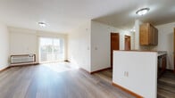 Located at 3148 Muir Field Rd in Madison, Wisconsin, this single-floor unit offers a well-organized and functional layout spread across several distinct living spaces. The main living area features wide-plank hardwood-style flooring that extends throughout much of the unit, complemented by warm wood baseboards and trim that add a cohesive, classic character. A sliding glass door with vertical blinds floods the living room with natural light and provides outdoor access. A ceiling fan adds comfort and airflow to the space.

The kitchen is positioned at the heart of the unit, anchored by a peninsula island that provides additional prep space and visual separation from the living area. Warm wood cabinetry, stainless steel appliances including a refrigerator, microwave, and range, along with dark countertops, complete the kitchen's practical and inviting design.

The bedrooms are carpeted for comfort, each featuring natural light through blinds-equipped windows, ceiling fans, and baseboard heating. The warm wood panel doors are consistent throughout the unit, reinforcing a unified aesthetic.

The full bathroom includes a tub-shower combination, a wood vanity with granite-style countertops, a large mirror, and hardwood-style flooring. A separate toilet room with a grab bar provides added convenience and accessibility. The unit's neutral color palette and clean finishes make it a versatile and welcoming space.