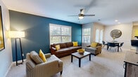 This thoughtfully designed 2-bedroom, 2-bathroom single-floor residence offers a comfortable and functional layout across a well-utilized footprint. The living room serves as the heart of the home, featuring a bold teal accent wall, plush carpeting, multiple windows with plantation shutters that invite generous natural light, and a ceiling fan overhead. Adjacent to the living area, the dining space is highlighted by French doors with exterior access, crown molding details, and a decorative wall panel, creating an elegant yet casual atmosphere. The kitchen is efficiently laid out with warm wood cabinetry, granite-style countertops, hardwood flooring, and a full suite of stainless steel appliances including a refrigerator, range, microwave, and dishwasher. The primary bedroom features a vibrant yellow accent wall, a ceiling fan, carpeted flooring, and natural light from multiple windows. The second bedroom offers a serene, neutral palette with coordinating nightstands and soft carpet. Both bathrooms include granite-top vanities, tub-shower combinations, and warm wood cabinetry. A dedicated in-unit laundry room with side-by-side washer and dryer, built-in shelving, and hardwood flooring adds everyday convenience. A closet and hallway complete the layout, ensuring ample storage throughout.