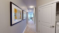 This single-floor, 2-bedroom, 2-bathroom residence offers a thoughtfully designed layout that maximizes comfort and functionality. The open-concept living, dining, and kitchen area serves as the heart of the home. The kitchen features rich cherry wood cabinetry, granite countertops, stainless steel appliances including a dishwasher and range, and a window overlooking greenery. The dining area is bathed in natural light from multiple large windows with wood-slatted blinds and is finished with durable hardwood-style flooring. The living room provides generous wall space, currently showcasing a curated gallery arrangement, and is finished with plush carpeting. A carpeted hallway, decorated with framed artwork, connects the private areas to the main living spaces. The spacious primary bedroom features a bold accent wall, large windows, and plush carpet. The second bedroom offers a similarly serene atmosphere with a soft accent wall and warm lighting. Both bedrooms include closets for storage. The two bathrooms are well-finished, one featuring tile flooring, a rich wood vanity with granite countertop, and a shower-tub combination. The space also includes a hallway and two closets, ensuring ample storage throughout.