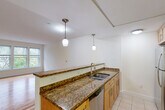 Located in Cambridge, MA, this 2-bedroom, 2-bathroom residence offers a well-organized single-floor layout designed for comfortable everyday living. The open kitchen and living room area serves as the heart of the home, featuring rich granite countertops, warm maple cabinetry, a stainless steel appliance suite including a refrigerator, range, microwave, and dishwasher, and tile flooring. A peninsula with pendant lighting provides additional prep space and a natural divide between the kitchen and the bright living area, which is finished with hardwood floors and natural light from a large window. The primary bedroom is a comfortable, carpeted retreat with multiple windows framing views of surrounding trees, creating a serene, nature-connected atmosphere. The second bedroom is similarly carpeted and well-proportioned, also benefiting from abundant natural light and greenery views. The full bathroom includes a tub-shower combination, a wood-toned vanity, and tile flooring. A second bathroom functions as a half bath and laundry space, maximizing utility. A hallway and closet round out the layout, keeping the floor plan organized and functional. The combination of granite finishes, stainless appliances, and natural light throughout gives this Cambridge residence a clean, polished character.
