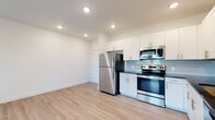 Located at 1100 Clearwater Largo Rd N in Largo, Florida, this single-floor unit offers a clean, modern aesthetic throughout its thoughtfully designed layout. The open-concept kitchen and living area form the heart of the space, anchored by light wood-look flooring that extends seamlessly across the main living areas. The kitchen is well-appointed with white shaker-style cabinetry reaching toward the ceiling, dark countertops, a light gray subway tile backsplash, and a full suite of stainless steel appliances including a refrigerator, range, microwave, and dishwasher. Recessed lighting illuminates the space efficiently throughout.

The living area is generously sized, featuring a ceiling fan, large windows fitted with blinds, and a glass door that opens to a private balcony with outdoor views of surrounding greenery. The bedroom is finished with plush carpeting and a window that brings in natural light and outdoor views.

The bathrooms showcase neutral, large-format tile work in warm taupe tones. One bathroom features a soaking tub with a tiled surround, while another offers a walk-in tiled shower with a mosaic-tiled floor. Both bathrooms maintain a cohesive, contemporary style that complements the overall design of the unit.