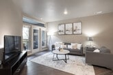 This 2-bedroom, 1-bathroom residence offers a thoughtfully designed single-floor layout that maximizes functionality and comfort. The open-concept living, dining, and kitchen area serves as the heart of the home, featuring warm hardwood-style flooring that flows throughout. The kitchen is equipped with dark espresso cabinetry, light quartz countertops, stainless steel appliances including a refrigerator, range, and microwave, and a central island with a double sink — ideal for both cooking and casual entertaining. A dedicated dining nook provides an intimate space for meals, while the living room offers generous natural light and direct access to a private outdoor area through double French doors. The two bedrooms are carpeted for comfort, each with windows that bring in natural light and ample space for furnishings. The primary bedroom includes a closet and room for a dresser and full-sized bed. The shared bathroom features dark cabinetry with a granite-topped vanity, a large mirror, wood-style flooring, and a shower-tub combination. Throughout the residence, neutral tones and modern finishes create a cohesive, contemporary aesthetic that is both functional and inviting.