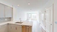 Located at 2000 Schindler Drive in South Amboy, NJ, this well-appointed one-bedroom, one-bathroom unit offers a thoughtfully designed open-concept layout with a bright, contemporary aesthetic throughout. Light wood flooring extends across the entire space, complementing the crisp white walls and recessed lighting that create a clean, modern atmosphere.

The kitchen and living area flow seamlessly together, anchored by a peninsula with a quartz countertop, undermount sink, and stainless steel dishwasher. The kitchen is fully equipped with gray shaker-style cabinetry, a herringbone tile backsplash, stainless steel gas range, and a built-in microwave — offering both style and functionality.

The living area is generously proportioned, filled with natural light from large windows and a glass door that opens to a private balcony overlooking a landscaped courtyard shared with the surrounding residential community.

The bedroom is a comfortable, sunlit retreat with a large window and light wood flooring, providing a serene environment. The bathroom features a full soaking tub and shower combination with clean white tile surrounds. A dedicated closet and an entryway with access to additional storage complete the layout, rounding out this efficiently designed and move-in-ready home.