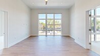 Located at 1600 Broadway in Sacramento's vibrant 95818 corridor, this modern 2-bedroom residence offers a thoughtfully designed single-floor layout with clean contemporary finishes. The open-concept kitchen and living area serves as the heart of the home, featuring light hardwood flooring, soaring ceilings, and a central kitchen island with a sleek light countertop and pendant lighting overhead. The kitchen is well-appointed with two-tone cabinetry — light upper cabinets paired with rich dark wood lower cabinets — and a full suite of stainless steel appliances including a refrigerator, range, and built-in microwave. Expansive floor-to-ceiling windows and sliding glass doors flood the living area with abundant natural light while framing views of Broadway's tree-lined streetscape. Both bedrooms are carpeted and bright, with the primary bedroom featuring a dedicated walk-in closet equipped with dual hanging rods. The second bedroom also benefits from large windows with street views. Throughout the residence, crisp white walls, tall ceilings, and a neutral palette create a clean, airy atmosphere well-suited for modern urban living.