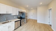 Located in Philadelphia's vibrant Fairmount neighborhood, this one-bedroom, one-bathroom unit offers a well-designed layout across a single living floor. The open-concept kitchen is outfitted with white shaker cabinets, a blue-gray subway tile backsplash, light quartz countertops, and a full suite of stainless steel appliances including a range, microwave, dishwasher, and refrigerator. Light wood-tone luxury vinyl flooring runs throughout the main living areas, lending a clean, contemporary feel. A glass-paneled door opens to a private balcony that frames sweeping views of the Philadelphia skyline, filling the living area with natural light. A dedicated utility room houses a stacked washer and dryer, providing the convenience of in-unit laundry. The bedroom is a comfortable, carpeted retreat featuring a double-door closet and neutral wall tones. The full bathroom is finished with large-format tile flooring, a rich espresso-toned vanity with white countertop, and a framed mirror. Recessed lighting throughout the unit adds to the bright, modern ambiance, making this a well-appointed urban residence in a prime Philadelphia location.