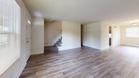 Located at 1114 Tace Dr in Essex, MD, this three-floor home offers a well-organized layout across its three levels. The main living floor features a comfortable living room with large windows that fill the space with natural light, complemented by durable wood-look flooring throughout. The kitchen is a functional highlight, featuring dark espresso cabinetry, granite-look countertops, a gas range, dishwasher, and a door providing direct exterior access — all finished with light hardwood-style flooring. The full bathroom is cleanly appointed with tile flooring, a dark-cabinet vanity, and a tub-shower combination. Upstairs, three bedrooms continue the warm, neutral palette with wood-look flooring, natural light from windows with blinds, and clean white trim throughout. The primary bedroom includes a closet and connects to the hallway. The lower level presents a spacious unfinished basement with a sealed, painted concrete floor, exposed wood-beam ceiling, painted block walls, and dedicated utility space housing laundry hookups and a furnace — offering strong potential for additional use or storage.