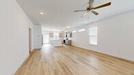 This well-appointed two-story home offers five bedrooms and three bathrooms across two thoughtfully designed floors of comfortable living space. The main floor features a bright, open-concept kitchen and living area finished with light hardwood-style flooring and crisp white walls. The kitchen is a standout, showcasing gray shaker-style cabinetry, a white center island, stainless steel appliances including a range and microwave, a subway tile backsplash, and pendant lighting. Transom windows along the upper walls allow additional natural light to fill the space, while a ceiling fan in the living area adds comfort. The main floor also includes a dedicated laundry room with utility hookups and an attached two-car garage with an automatic opener. Upstairs, five bedrooms provide ample accommodation, with carpeted floors adding warmth and comfort. The generously sized primary bedroom connects to an en-suite bath and features a spacious walk-in closet with built-in wire shelving. Secondary bedrooms include standard closets with wire rod systems. The bathrooms are finished with gray vanity cabinetry, white countertops, and tub-shower combinations with clean, modern fixtures. The home's neutral palette and consistent finishes throughout create a cohesive and move-in-ready living environment.