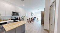 Located at 7207 McKnight Rd in Pittsburgh's North Hills, this thoughtfully designed one-bedroom, one-bathroom residence offers a clean, modern aesthetic across a well-utilized single floor. The open-concept kitchen and living area serves as the heart of the home, featuring light hardwood-style flooring, recessed lighting, and a bright, airy atmosphere. The kitchen is outfitted with stainless steel appliances including a refrigerator, electric range, microwave, and dishwasher, complemented by two-tone cabinetry — crisp white uppers and gray lowers — white subway tile backsplash, white quartz countertops, and a movable island with a butcher block top for added prep space and flexibility. The living area flows naturally from the kitchen, offering ample room for dining and lounging, with natural light streaming in from a sliding glass door that leads to a private balcony. The bedroom is a comfortable retreat with plush carpeting, a walk-in closet featuring wire shelving, and a window that fills the room with natural light. The bathroom is finished with light wood-look tile flooring, a sleek vanity, and a large walk-in shower enclosed by frameless glass doors with white tile surround. Clean lines and a neutral palette create a cohesive, contemporary feel throughout.