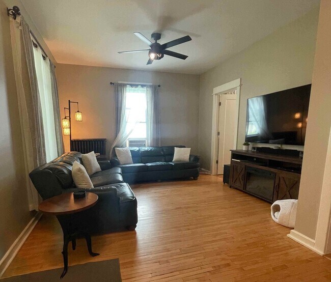 Amplia sala de estar con muchos asientos, televisor grande y aire acondicionado de ventana según la temporada. - 1901 -2301 Fillmore Street NE Minneapolis, MN 55418