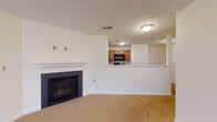 This single-floor residence offers a well-organized layout with a clean, neutral aesthetic throughout. The living area serves as the heart of the home, anchored by a classic fireplace with a white mantel and black surround, set against crisp white walls and warm beige carpeting. An open pass-through connects the living space directly to the kitchen, which features medium-tone wood cabinetry, black appliances including a refrigerator, range, and microwave, and durable tile flooring in a stone-like finish.

The bedrooms are generously sized, each featuring soft carpeting, ceiling fans with integrated lighting, and large windows that invite natural light and outdoor views of surrounding trees. The rooms offer ample wall space and closet access, providing functional versatility.

Two bathrooms serve the residence. The full bathroom includes a tub-shower combination, a wood-vanity with a light countertop, and the same tile flooring found in the kitchen. A half bath provides a toilet and sink for added convenience.

A dedicated laundry area with washer and dryer hookups adds practical value. Throughout the home, white panel doors, chrome fixtures, and consistent neutral tones create a cohesive, move-in-ready environment.