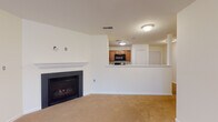 This single-floor residence offers a well-organized layout with a clean, neutral aesthetic throughout. The living area serves as the heart of the home, anchored by a classic fireplace with a white mantel and black surround, set against crisp white walls and warm beige carpeting. An open pass-through connects the living space directly to the kitchen, which features medium-tone wood cabinetry, black appliances including a refrigerator, range, and microwave, and durable tile flooring in a stone-like finish.

The bedrooms are generously sized, each featuring soft carpeting, ceiling fans with integrated lighting, and large windows that invite natural light and outdoor views of surrounding trees. The rooms offer ample wall space and closet access, providing functional versatility.

Two bathrooms serve the residence. The full bathroom includes a tub-shower combination, a wood-vanity with a light countertop, and the same tile flooring found in the kitchen. A half bath provides a toilet and sink for added convenience.

A dedicated laundry area with washer and dryer hookups adds practical value. Throughout the home, white panel doors, chrome fixtures, and consistent neutral tones create a cohesive, move-in-ready environment.