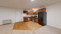 Located at 111 Regent Dr in Dover, New Hampshire, this 2-bedroom, 1-bathroom residence offers a practical and well-organized single-floor layout. The open-concept kitchen and living area serves as the heart of the home, with the kitchen showcasing warm medium-toned wood cabinetry extending to the upper walls, stainless steel appliances including a dishwasher, electric range, and over-the-range microwave, complemented by light hardwood flooring. The living area transitions seamlessly from the kitchen and is finished with plush wall-to-wall carpeting, creating a comfortable and cohesive space. Both bedrooms are carpeted and bright, each featuring windows that invite natural light and views of the surrounding greenery, along with baseboard heating. The primary bedroom is generously sized and provides access to dedicated closet space. The shared bathroom is finished with neutral tile flooring and includes a wood-toned vanity with ample counter space, a bathtub, and clean white walls that give the room an open feel. Two closets throughout the home provide practical storage solutions. The overall aesthetic is clean and neutral, with white walls throughout creating a versatile canvas well-suited for personalization.