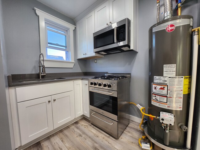 Kitchen features a modern gas stove with an over the counter microwave. - 301 Broad St