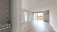 Located at 13729 Via Del Palma Ave in Whittier, CA, this one-bedroom, one-bathroom unit offers a well-organized single-floor layout encompassing a living room, kitchen, bedroom, bathroom, entrance, hallway, and closet. The living room is a bright, open space finished with light wood-style flooring, neutral gray walls, and a textured ceiling. A sliding glass door fitted with vertical blinds opens to a private balcony, allowing natural light to pour in and providing outdoor views of surrounding greenery. A wall-mounted air conditioning unit ensures year-round comfort. The galley-style kitchen features white cabinetry, laminate countertops, a double-basin sink, white appliances including a range and refrigerator, and track lighting overhead. A window with vertical blinds and a frosted glass accent panel bring additional light into the space. The bedroom offers a comfortable footprint with plush carpeting, a large window, a textured ceiling, and access to a dedicated closet. The bathroom is equipped with a shower-tub combination, a white vanity with storage, and wood-style flooring. The entrance hallway also features wood-style flooring, providing a cohesive transition throughout the unit. Overall, the space presents a clean, neutral palette ideal for a variety of living arrangements.