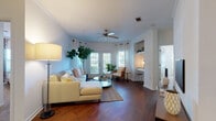 Located at 8108 Vinoy Blvd in Charlotte, NC, this well-appointed single-floor residence offers a thoughtfully designed layout with a bright, welcoming ambiance throughout. The spacious living room is a standout feature, showcasing rich hardwood flooring, a ceiling fan, and multiple windows dressed with sheer curtains that flood the space with natural light. French doors provide an attractive focal point and further enhance the airy feel of the room. A built-in nook adds a charming architectural detail to this central gathering space. Adjacent to the living room, the dining area features hardwood floors, crown molding, a pendant light fixture, and a wall mirror that amplifies the sense of space. The galley-style kitchen is outfitted with warm wood cabinetry, dark countertops, a stainless steel sink, and black appliances, offering a functional and efficient workspace. The primary bedroom is carpeted for comfort, with a ceiling fan and a large window allowing for natural light. A second bedroom also features plush carpet, a ceiling fan, and direct access to a bathroom. The bathroom presents hardwood-style flooring, a dark-topped vanity, and clean white cabinetry. Throughout the residence, a consistent palette of soft whites and warm wood tones creates a cohesive, inviting atmosphere.